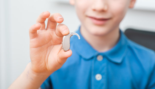 为儿童做助听器广告，一个白人男孩展示助听器。儿童听力治疗图片下载