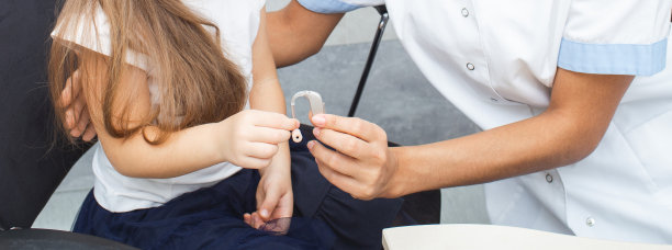 听力学家和她的小病人正拿着助听器。一个医生和一个带助听器的病人的手的特写。听到诊所图片下载