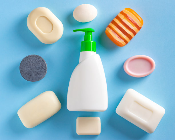 肥皂液分配器瓶和许多不同类型的肥皂棒在蓝色背景。勤洗手，抗病毒防护。俯视图，平放图片下载