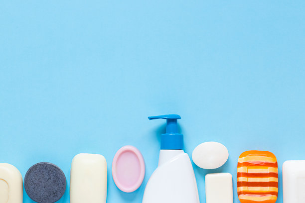 瓶子的液体肥皂和许多不同类型的肥皂棒在蓝色的背景。勤洗手，抗病毒防护。俯视图，文本空间图片下载