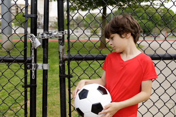 小男孩在关闭锁定的运动场旁图片下载