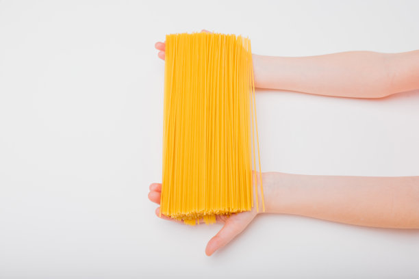 特写，意大利面条在两个孩子的手孤立的白色图片下载