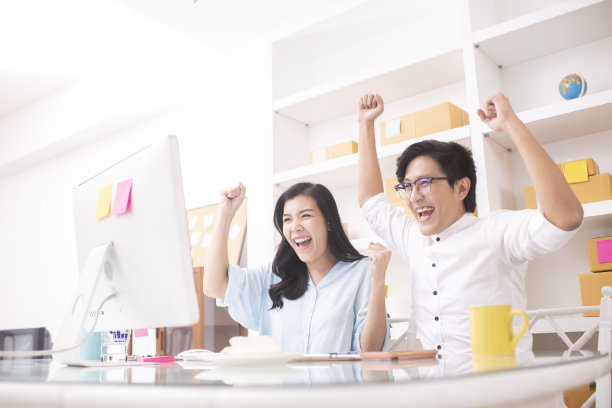 亚洲小企业主夫妇庆祝成功与幸福的感觉在电脑前在家办公。在线业务的概念图片下载