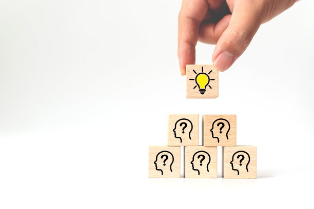 概念、创意、想法和创新。手工挑选木质立方体块与灯泡图标顶部金字塔和头部人类象征图片下载