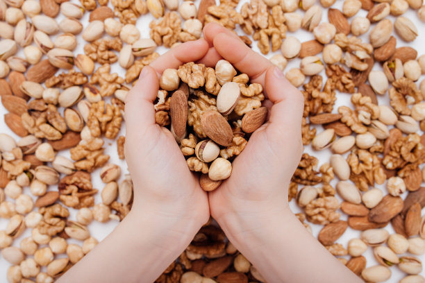 什锦坚果在孩子手中核桃，开心果，杏仁，榛子图片下载