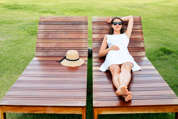 年轻女子躺在木制躺椅上休息图片下载
