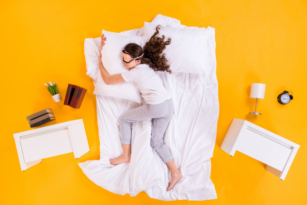 舒适地躺在卧室里拥抱枕头的漂亮小女孩俯视全身照图片下载