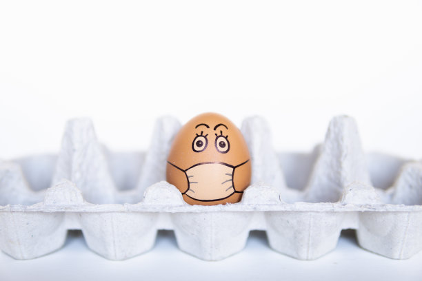 鸡蛋在托盘上涂鸦脸戴着医用口罩。冠状病毒隔离期间居家的概念形象图片下载