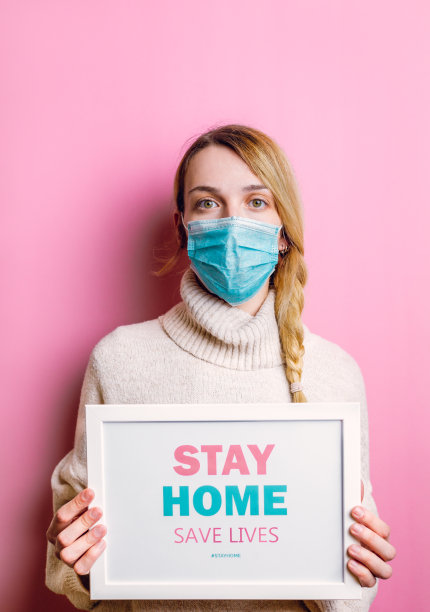 戴着防护口罩的女人拿着“居家，拯救生命”的励志标语图片下载