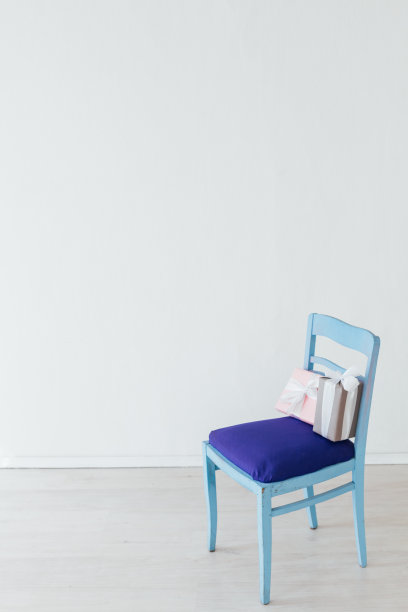 在一个白色的空房间里，一张带礼物的蓝色椅子图片下载