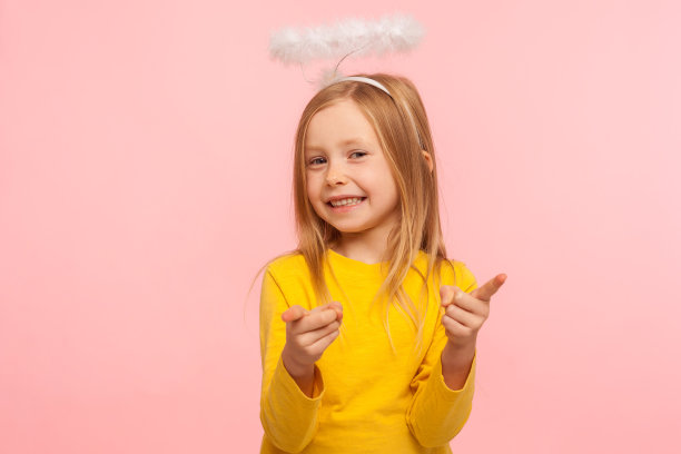 嘿,你们真幸运啊!快乐可爱的小女孩与天使光环指向相机和看着相机图片下载