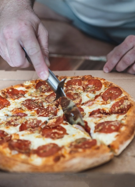 裁剪男性的手切玛格丽塔披萨与意大利辣香肠与特殊的刀，特写图片下载