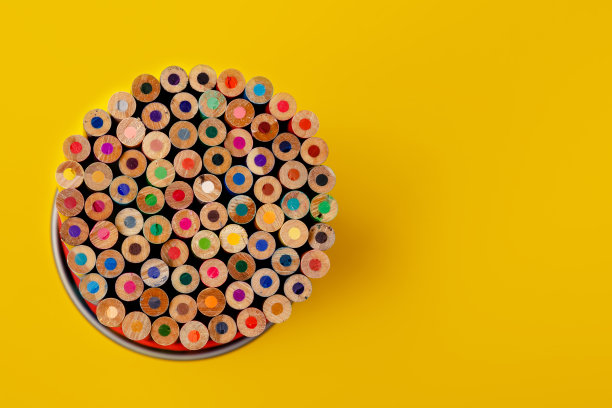 彩色铅笔在金属支架上黄色的背景。免费空间图片下载