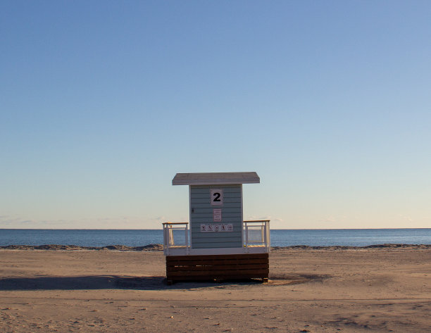 清晨，救生员在空旷的海滩上小屋，天空湛蓝无云。图片下载