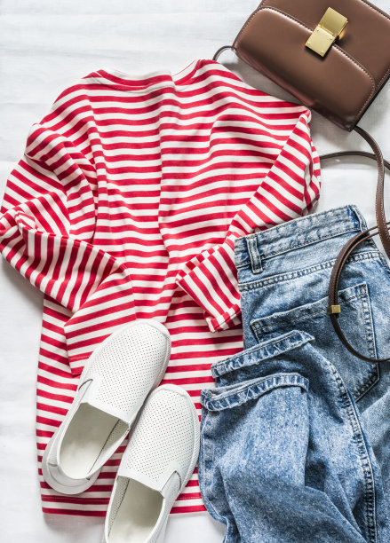 女式长袖t恤，红色条纹，蓝色妈妈牛仔裤，运动鞋和斜身棕色皮包在一个浅的背景，俯视图。时尚的概念图片下载