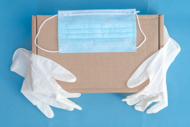 不同的医用手套与硬纸盒，在病毒检疫邮件货物交付的概念，横幅与副本空间在蓝色背景图片下载