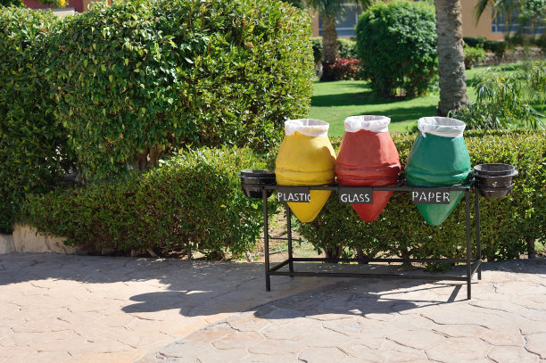 三个垃圾分类回收容器。酒店海滩上的纸、玻璃、塑料垃圾容器上有黄色、红色、绿色标记。生态的概念图片下载
