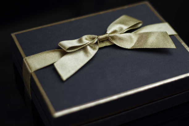 特写深蓝色礼盒和金色丝带在黑色的背景图片下载