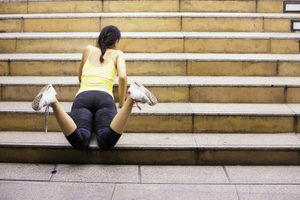 跑步者摔倒。在城市楼梯上奔跑的女人。在城市里，运动员从楼梯上摔了下来。健身、运动、人、锻炼和生活方式。图片下载