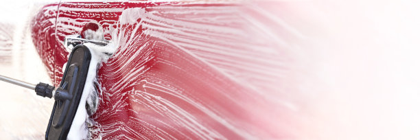 在自助洗车店洗过的红色汽车，侧门上有详细的笔触，右侧有空白的宽幅横幅图片下载