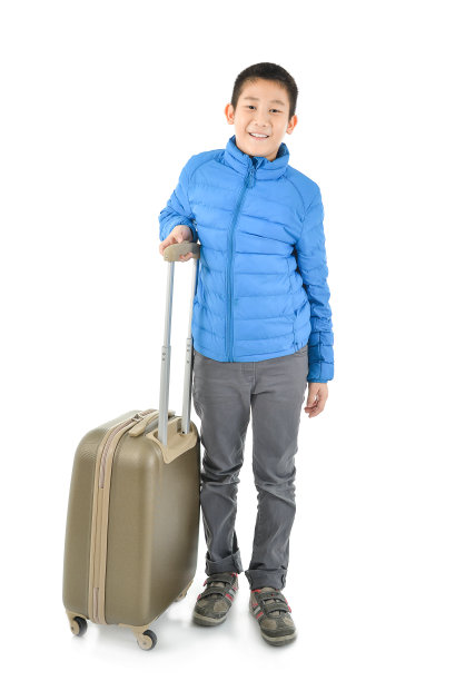 快乐的亚洲男孩穿着蓝色羽绒服和一个手提箱。对白色的隔离图片下载