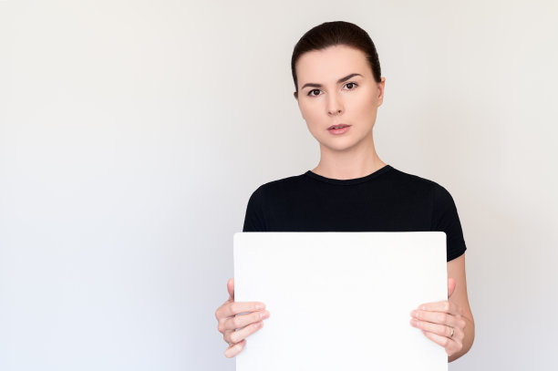 一位黑头发棕色眼睛的美女，身穿黑色t恤，白色背景，手里拿着一个没有文字的平板电脑。为文本复制空间。肖像的媒介计划图片下载