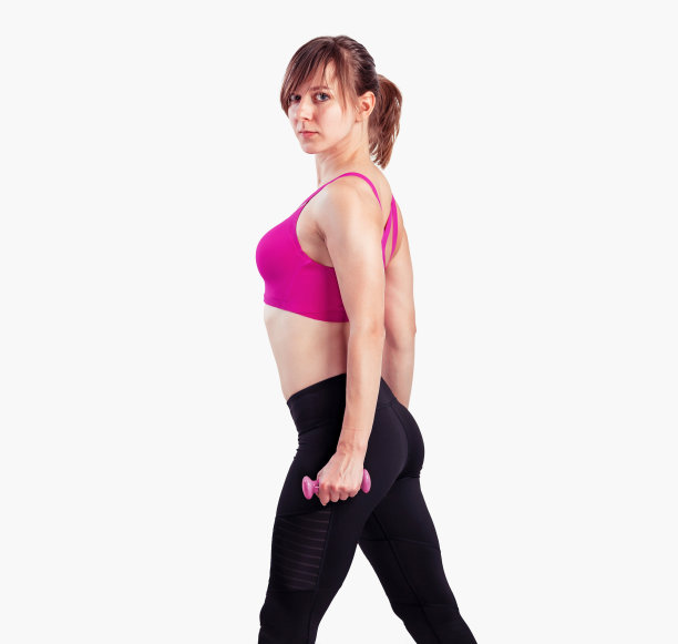 运动女性在灰色背景下用哑铃做练习。照片肌肉女性在运动装在工作室图片下载