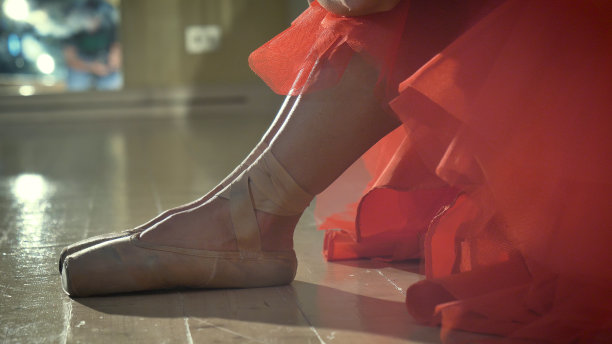 一个美丽的轻芭蕾舞女演员的肖像，在一个茂盛的红色连衣裙，练习舞蹈作为激情。图片下载