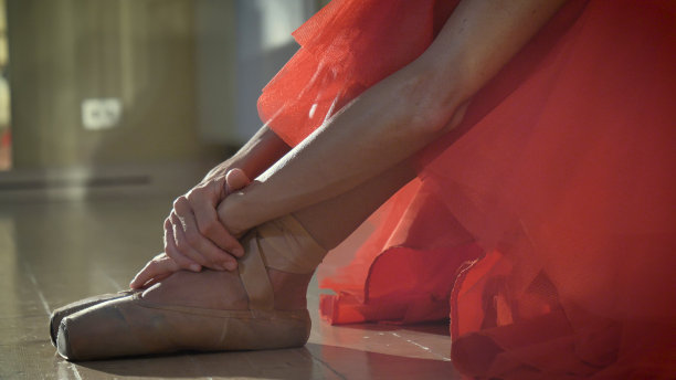 一个美丽的轻芭蕾舞女演员的肖像，在一个茂盛的红色连衣裙，练习舞蹈作为激情。图片下载