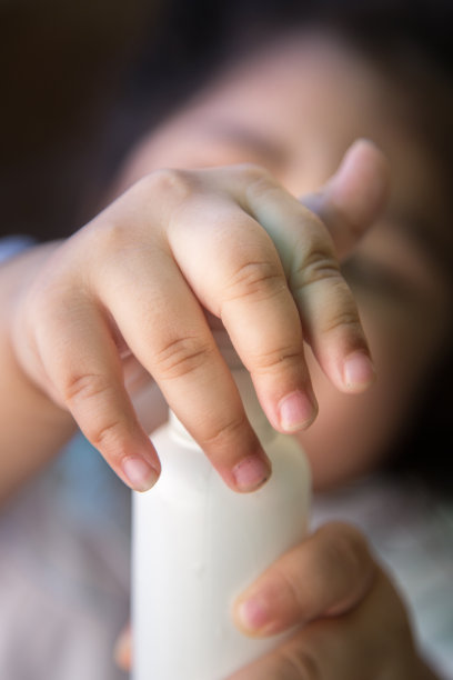 靠近拿着消毒洁面胶的瓶子的孩子。儿童使用酒精洗手液预防冠状病毒和Covid-19大流行。图片下载