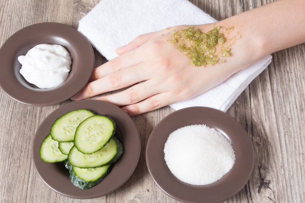 皮肤护理在家。一位妇女将自制的天然磨砂膏涂在手上。磨砂膏的配料，盐，糖，黄瓜，奶油。保湿、去角质、去角质、SPA、美容院。生态图片下载