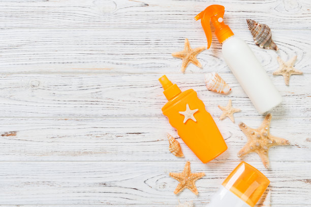 带贝壳的防晒霜瓶子放在有复印空间的白色木桌上。旅行保健配件俯视图图片下载