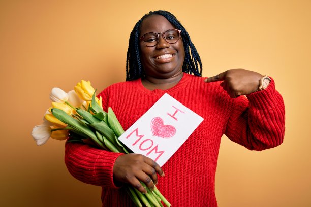 大尺寸的非裔美国妇女在母亲节拿着爱妈妈的信息和郁金香惊讶地指着自己的脸图片下载
