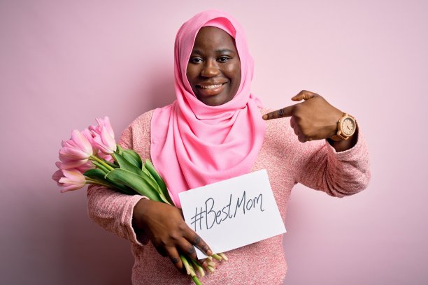 大码非裔美国妇女戴着头巾，拿着母亲节郁金香和惊喜表情图片下载