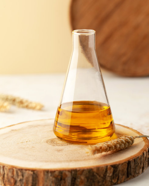 有机植物油在一个玻璃烧瓶和小麦小穗木架上，有文字空间。垂直的照片。图片下载