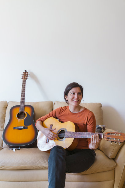 开朗美丽的白人女性学习如何演奏一种乐器。图片下载