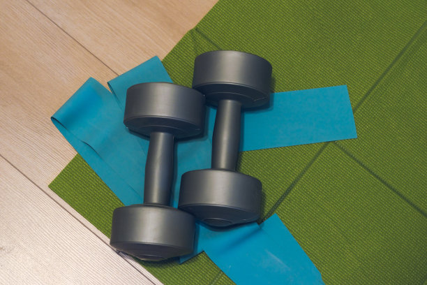 哑铃，瑜伽垫和弹性健身在一个轻层压板在家里，一个地方，你的文本。家庭运动拷贝空间图片下载
