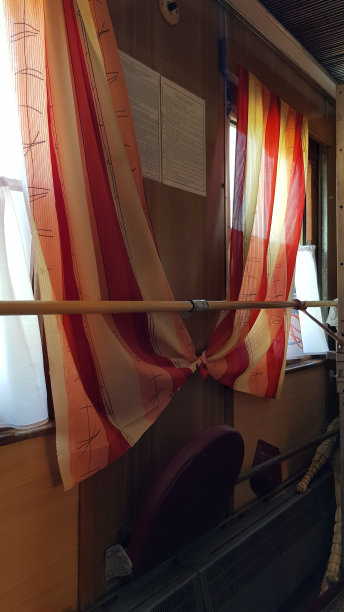 旧火车车厢内的复古内饰。苏联时期过时火车走廊上的窗户和系着的窗帘。图片下载