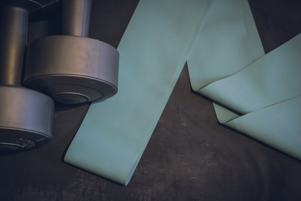 哑铃和橡皮筋的健身在一个深灰色的石头背景，地方为您的文本。家庭运动拷贝空间图片下载