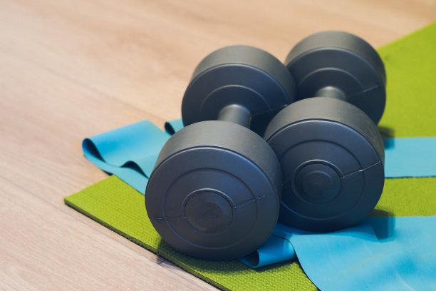 哑铃，瑜伽垫和弹性健身在一个轻层压板在家里，一个地方，你的文本。家庭运动拷贝空间图片下载