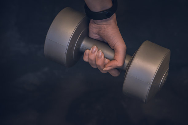 哑铃和橡皮筋的健身在一个深灰色的石头背景，地方为您的文本。家庭运动拷贝空间图片下载