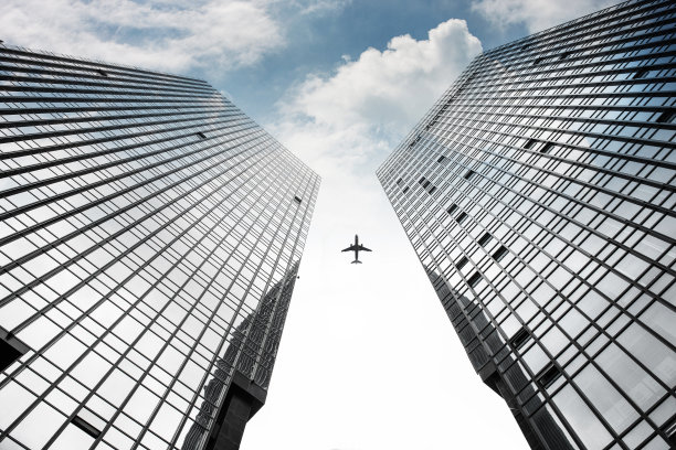 飞机飞越两座对称的城市建筑图片下载