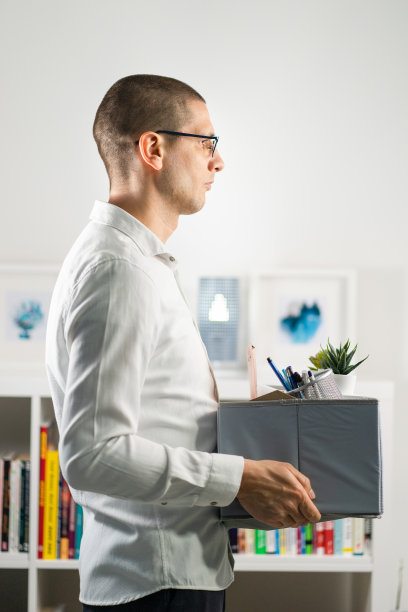 这是一幅成年白人男子穿着白衬衫拿着盒子私人物品离开办公室因经济危机失业公司倒闭而被解雇的照片图片下载