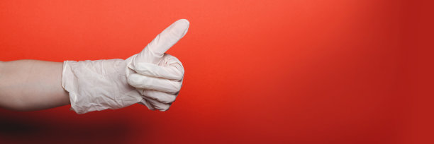 孩子的手在大医疗手套显示拇指向上的红色背景图片下载