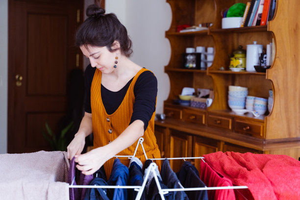 孤立的中年妇女在家里晾湿衣服。图片下载