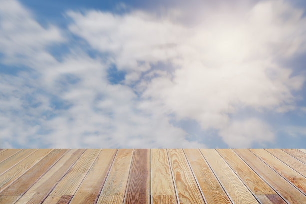 模糊多云的天空和阳光背景与木地板前景户外放松一个夏天。图片下载