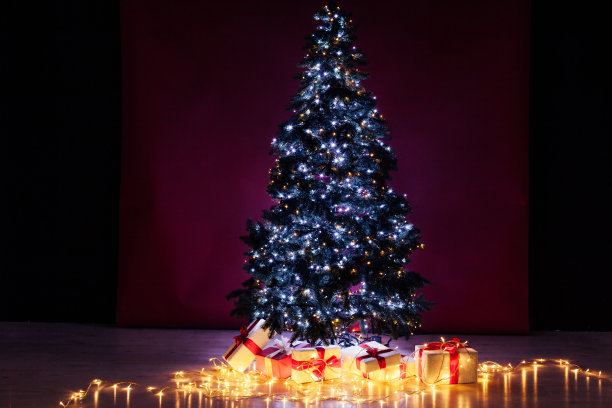 圣诞树花环灯与新年礼物的红色背景素材图片