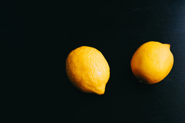 黑色背景上的新鲜柠檬。两个柠檬。图片下载