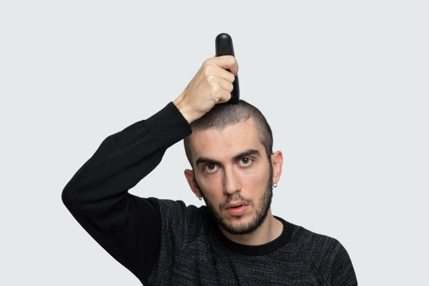 年轻人剪自己的头发İsolated灰色背景图片下载