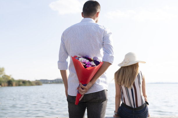 那个快乐的男人在公园里给一个女人送花。一个男人在一个夏日给他的爱人送花的照片。浪漫的情侣图片下载